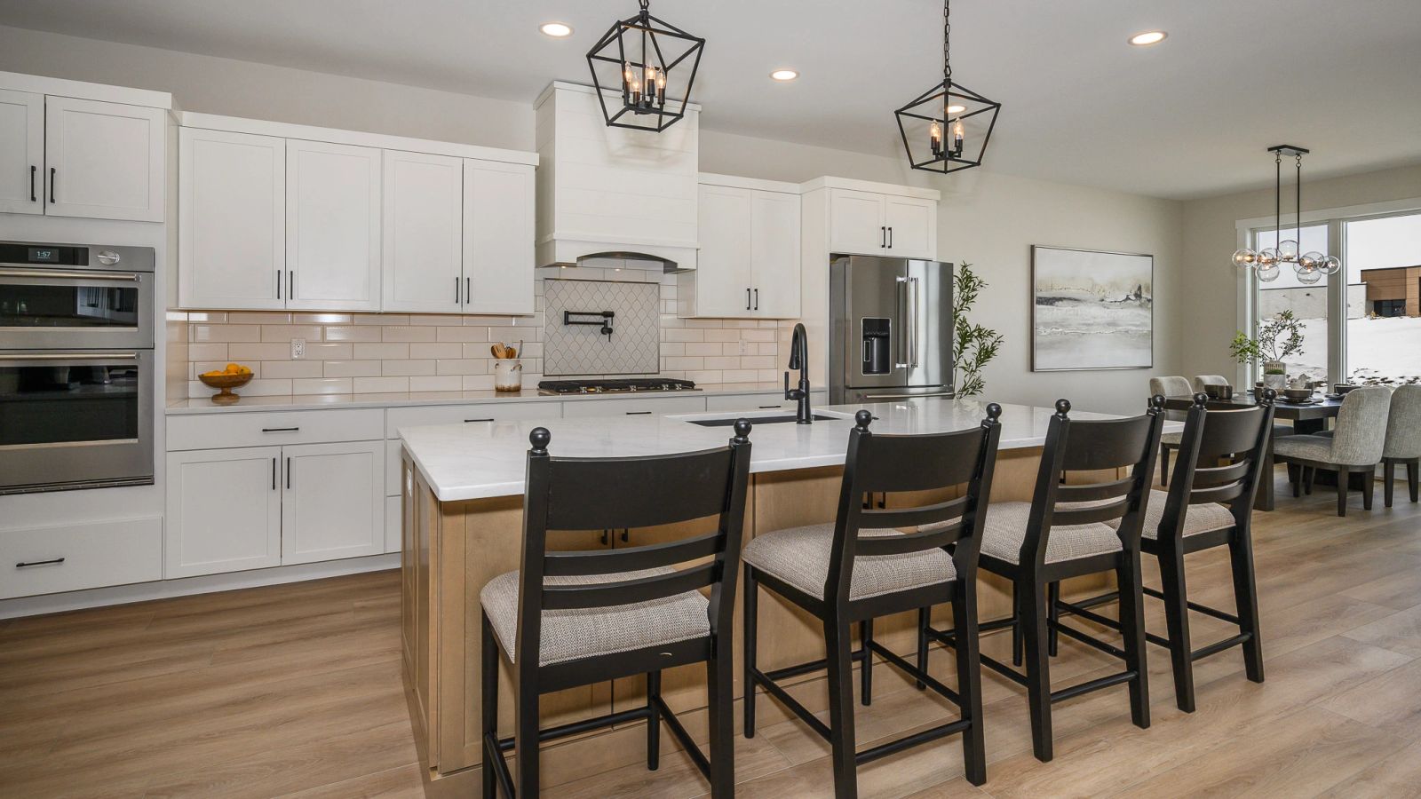 A Huntington Builders kitchen with white cabinets, a wood island and black fixtures.